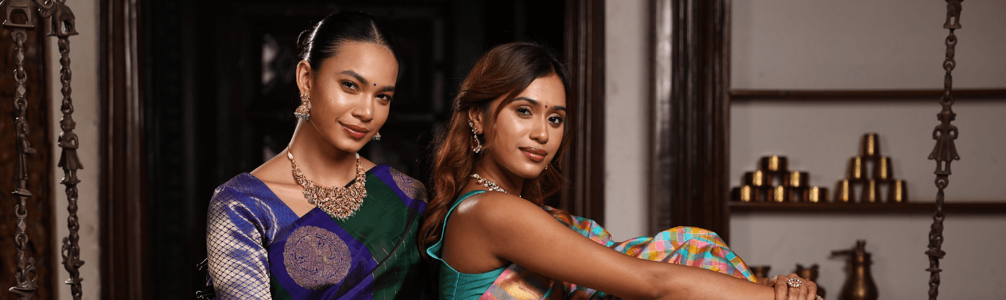 Two women in draped sarees and jewellery